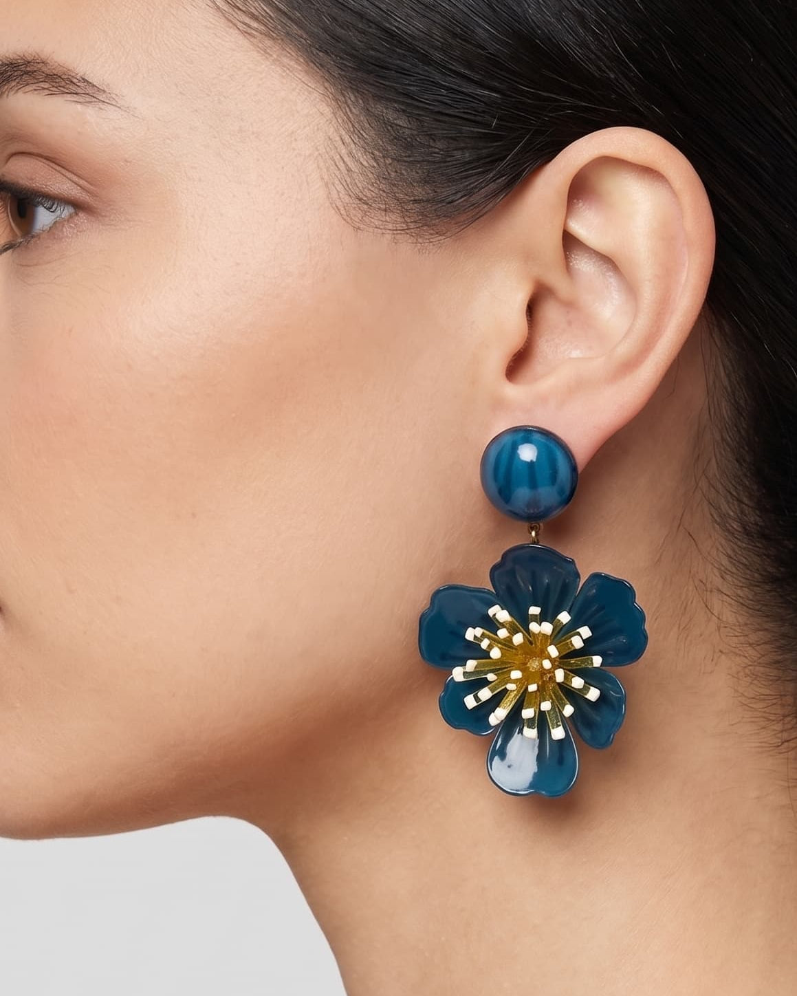 vista de perfil del pendiente de flor azul de Ciléa Paris colocado en el lóbulo de una modelo, luciendo su caída, su escala maxi de 7.5x4.5 cm y su elegante sistema de cierre de clip.