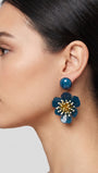 vista de perfil del pendiente de flor azul de Ciléa Paris colocado en el lóbulo de una modelo, luciendo su caída, su escala maxi de 7.5x4.5 cm y su elegante sistema de cierre de clip.