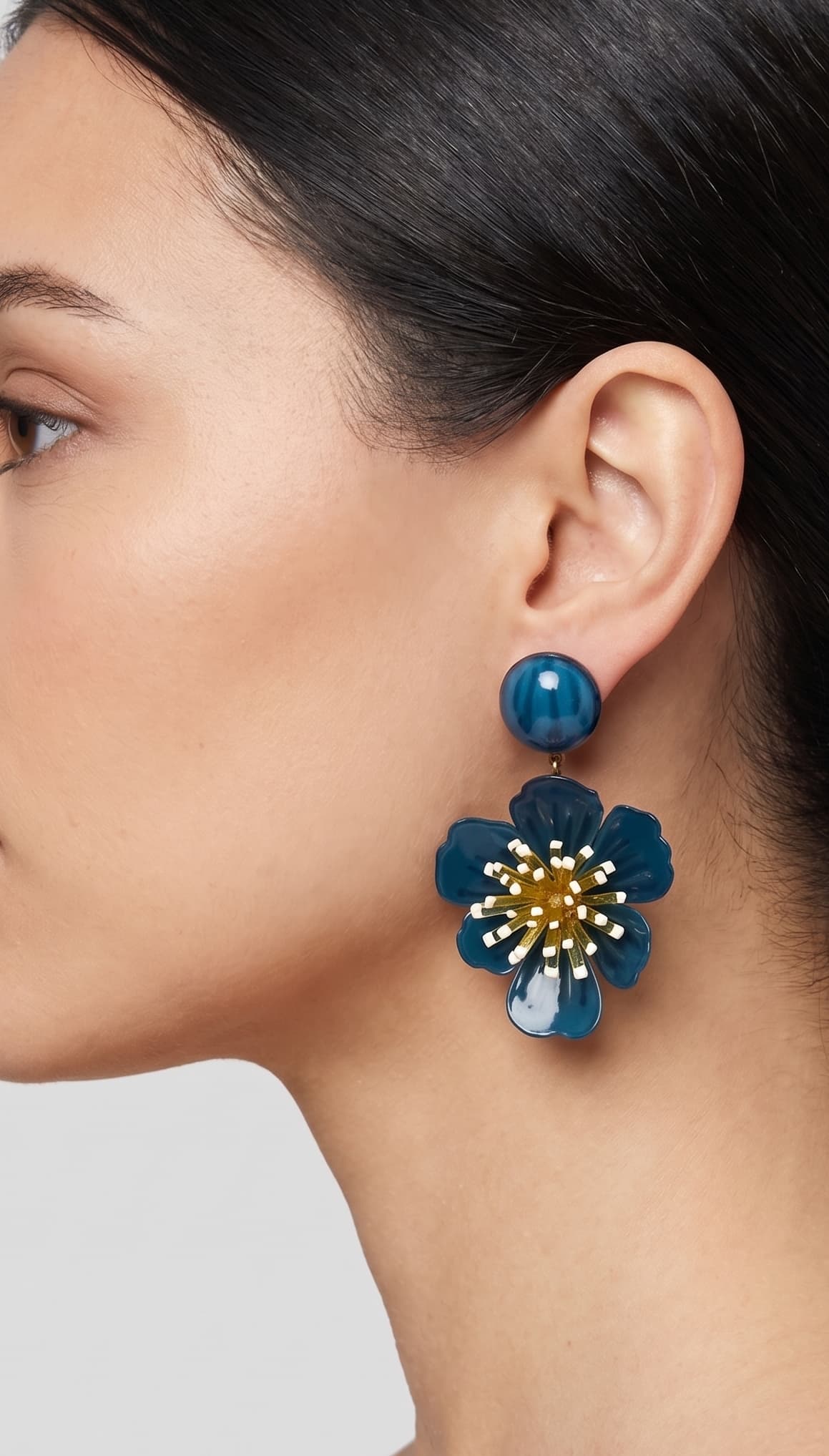 vista de perfil del pendiente de flor azul de Ciléa Paris colocado en el lóbulo de una modelo, luciendo su caída, su escala maxi de 7.5x4.5 cm y su elegante sistema de cierre de clip.