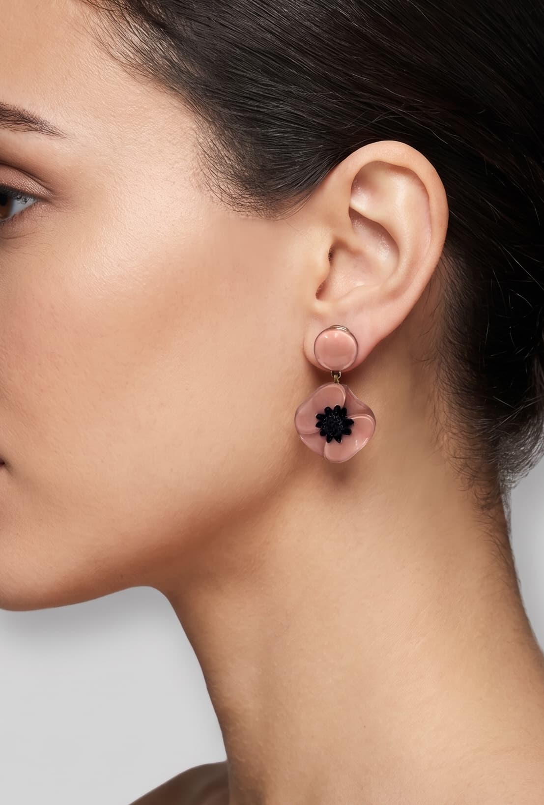 Vista de perfil del pendiente de amapola rosa de Ciléa Paris colocado en una modelo, detallando el ajuste de su cierre de pinza y su escala elegante.