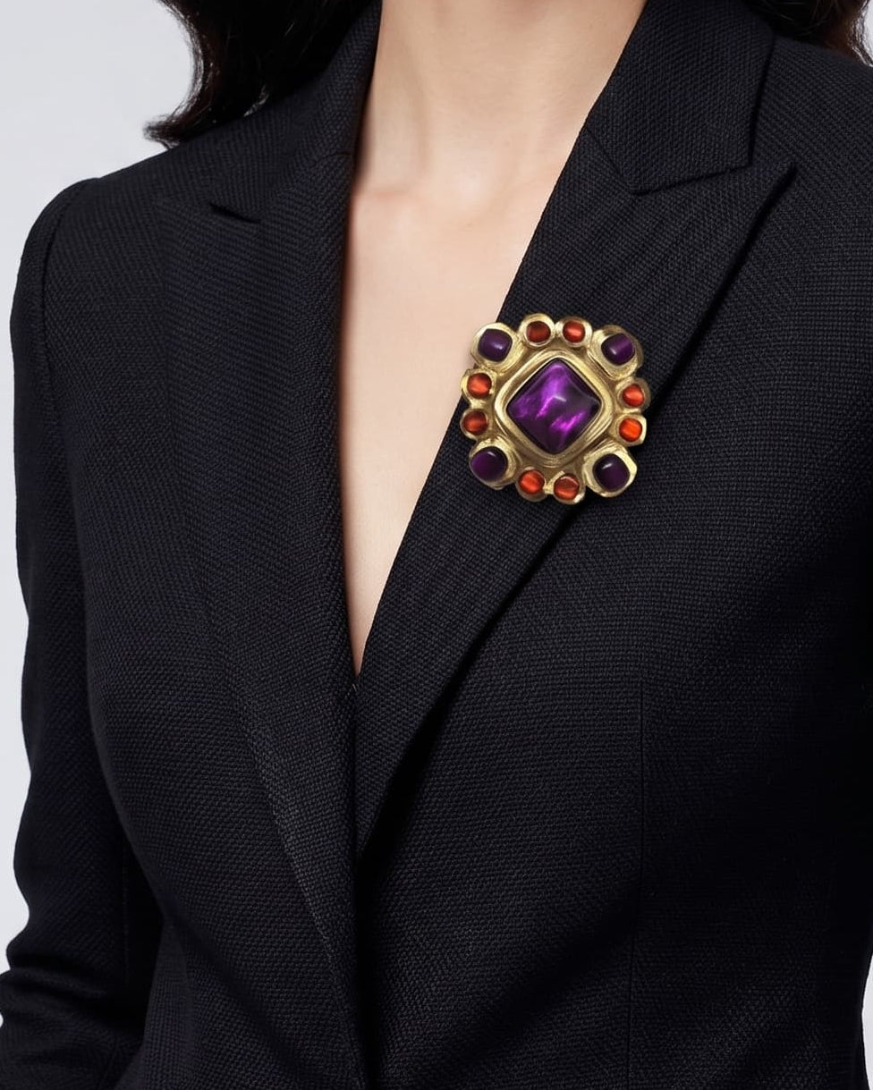 modelo luciendo el broche bizantino Petit Violette en la solapa de una americana negra, apreciando su proporción y acabado iridiscente.