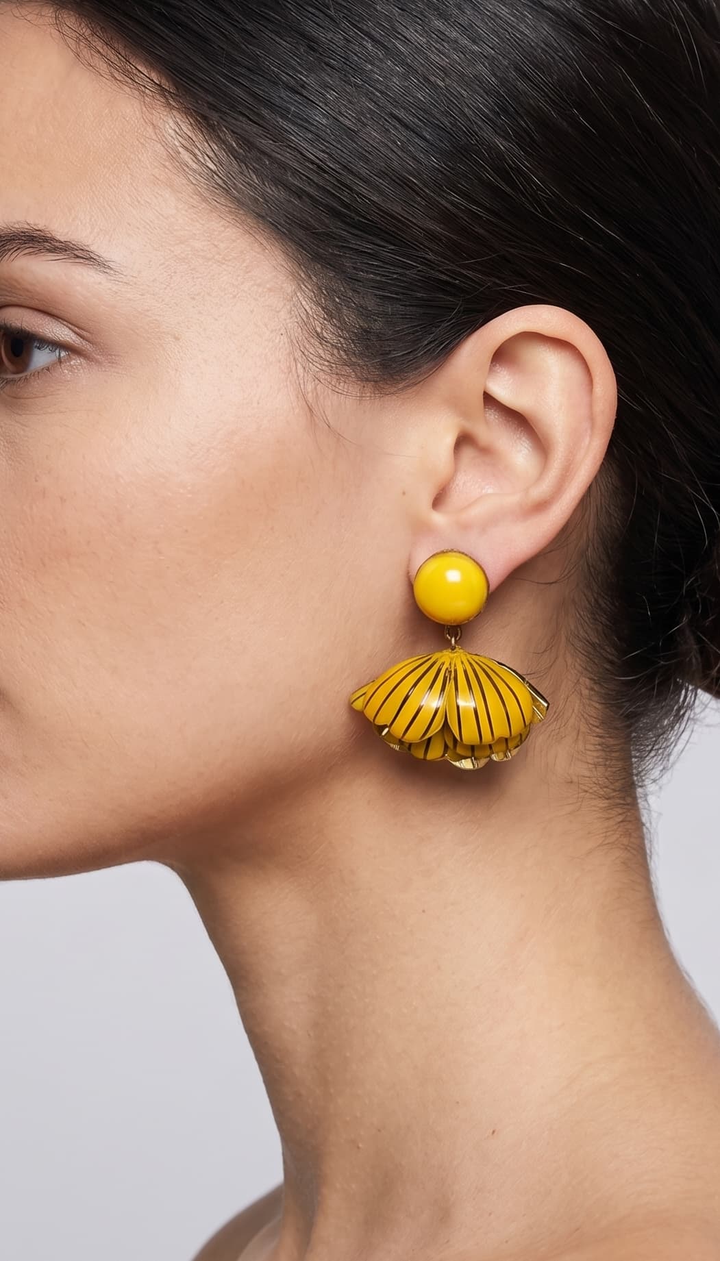 vista de perfil del pendiente amarillo de Ciléa Paris colocado en una modelo, detallando el ajuste de su cierre de pinza y su elegante escala tridimensional.