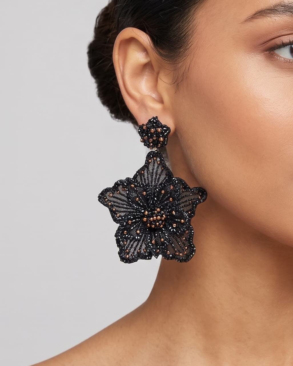 modelo luciendo el pendiente Fleur Noire en la oreja, apreciando su silueta maxi y volumen floral sobre la piel.