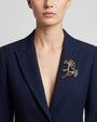 Vista de una blazer azul marino con el broche "Brote de Invierno" colocado en la solapa izquierda, resaltando su tamaño.