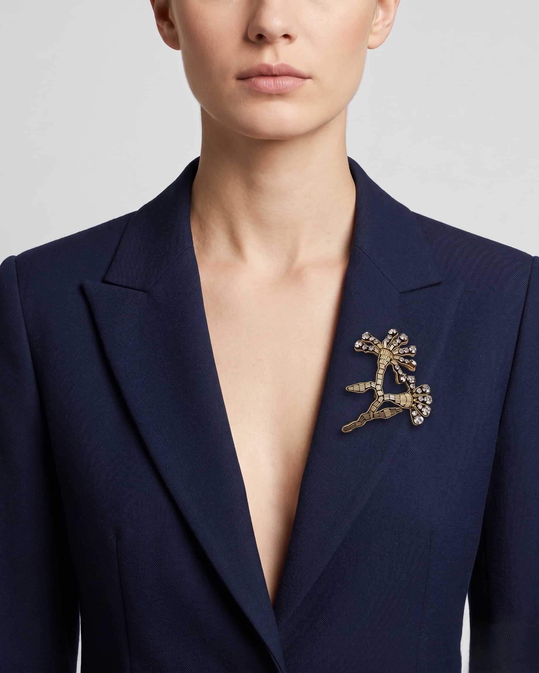 Vista de una blazer azul marino con el broche "Brote de Invierno" colocado en la solapa izquierda, resaltando su tamaño.