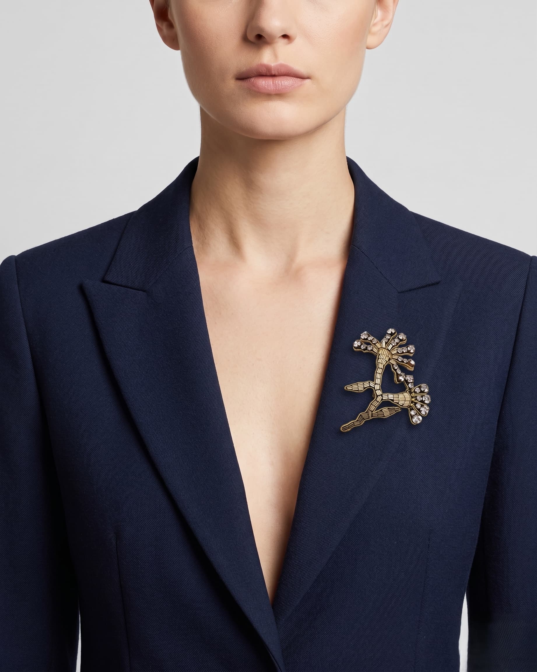 Vista de una blazer azul marino con el broche "Brote de Invierno" colocado en la solapa izquierda, resaltando su tamaño.