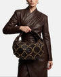 modelo luciendo el bolso Ginebra en la mano, apreciando su silueta curva, su gran escala y su estilo bohemio chic.