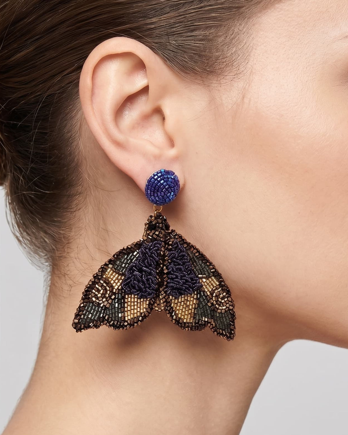 modelo luciendo el pendiente Papillon de Nuit en la oreja, apreciando su silueta de alas desplegadas y volumen sobre la piel.