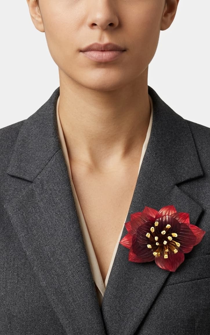 modelo de frente luciendo el broche maxi de loto rojo prendido en la solapa de una americana de sastre gris oscuro, mostrando su escala sofisticada y elegante.