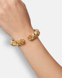 modelo luciendo la pulsera Cosima en la muñeca, apreciando la calidez del oro y la anchura escultural de la caña.
