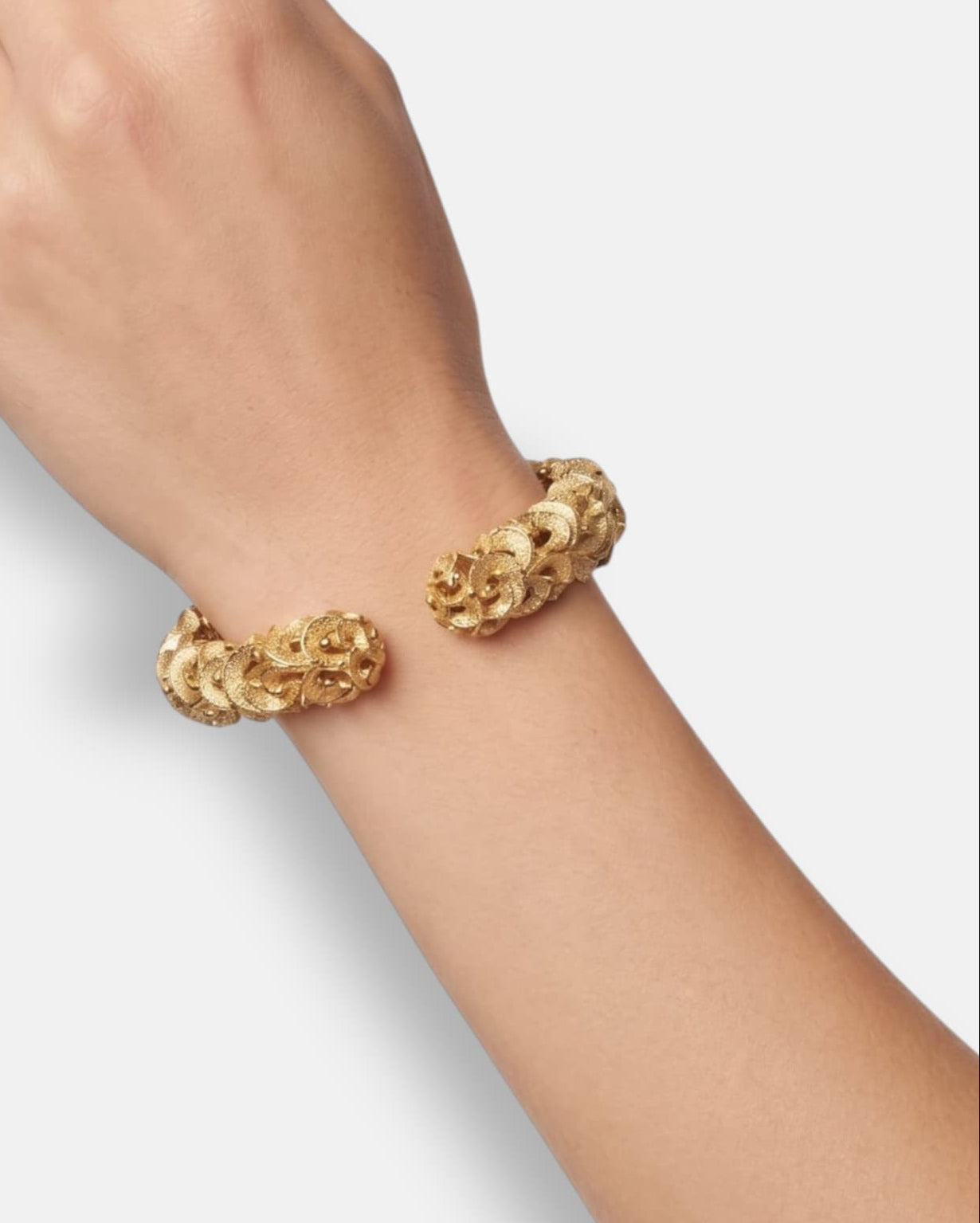 modelo luciendo la pulsera Cosima en la muñeca, apreciando la calidez del oro y la anchura escultural de la caña.