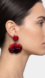 modelo luciendo el pendiente colgante de amapola roja, apreciando su escala maximalista, su relieve tridimensional y cómo adorna el rostro con sofisticación.