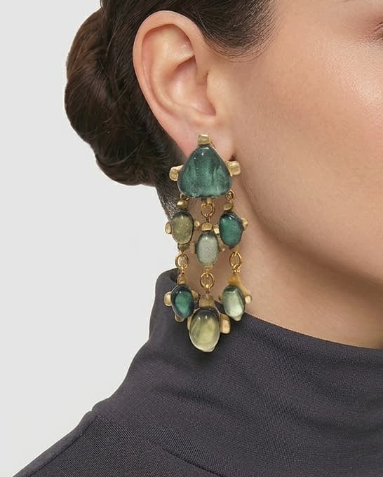 modelo luciendo los pendientes Penelope Émeraude en la oreja, apreciando su longitud escultural y destellos verdes sobre la piel.