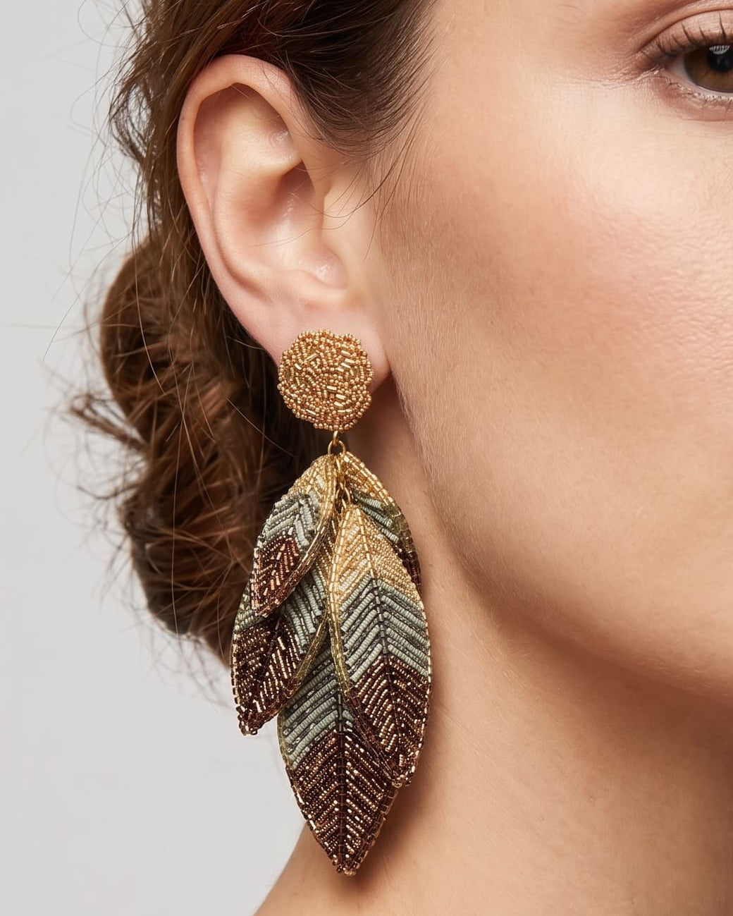modelo luciendo los pendientes Feuille Bronze, apreciando su caída estilizada, brillo metalizado y escala sobre la piel.