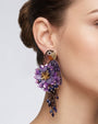 modelo luciendo el pendiente Perroquet Violet en la oreja, apreciando su silueta de ave, volumen floral y escala sobre la piel.