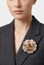 vista frontal del broche de flor de Ciléa Paris colocado en la solapa de una chaqueta de sastre gris, detallando su escala maxi y su elegancia.