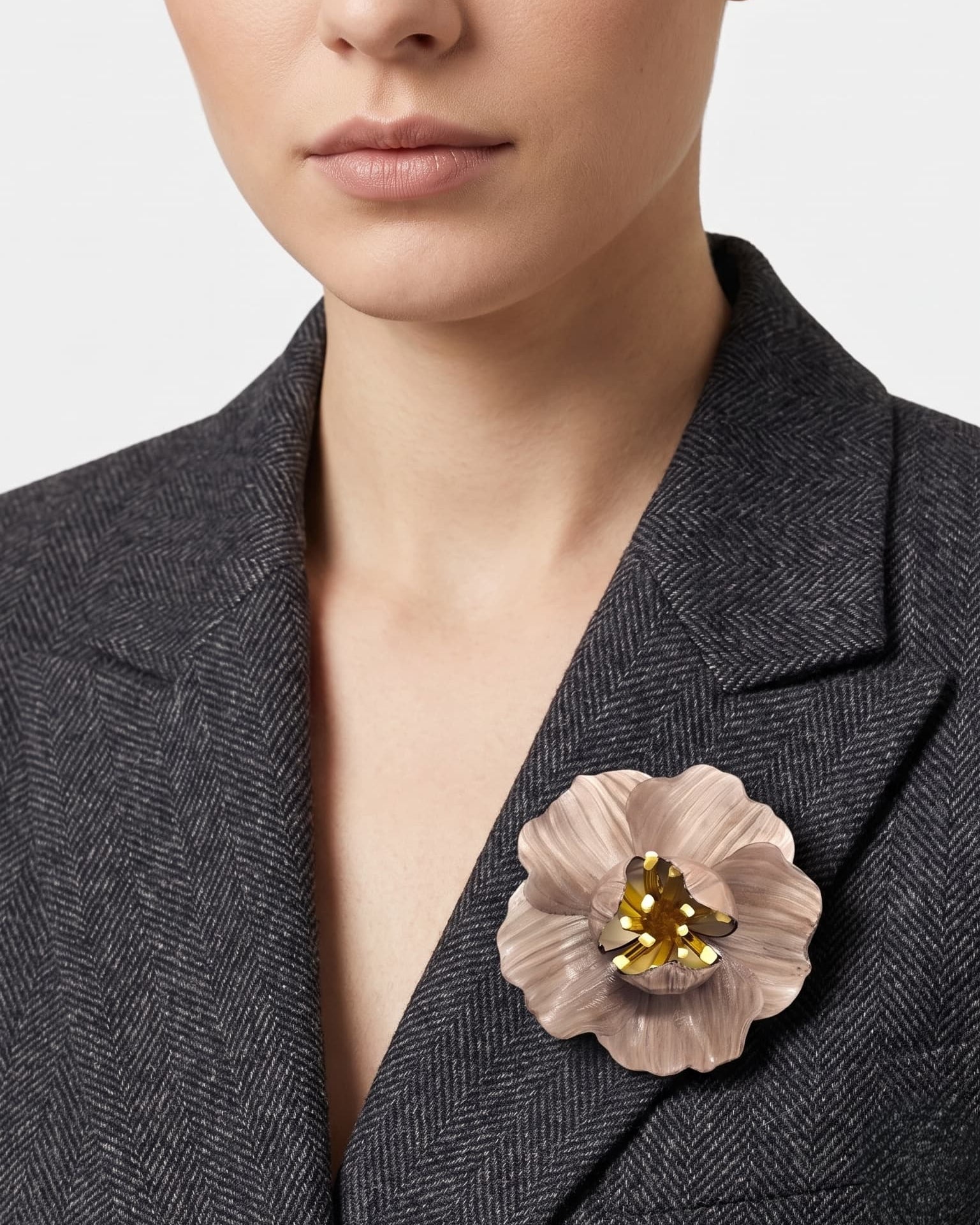 vista frontal del broche de flor de Ciléa Paris colocado en la solapa de una chaqueta de sastre gris, detallando su escala maxi y su elegancia.