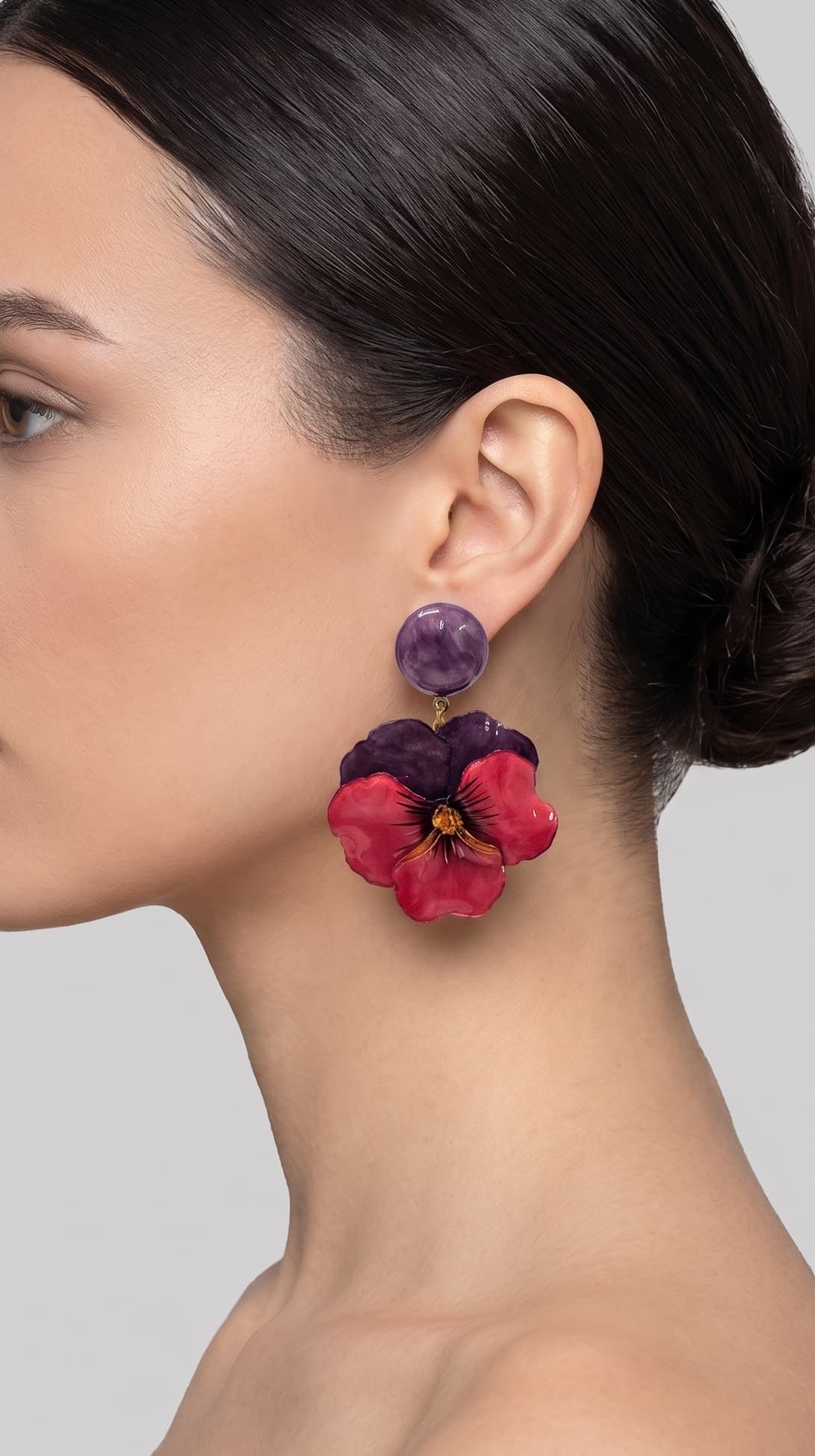 vista de perfil del pendiente de pensamiento violeta y rojo de Ciléa Paris colocado en el lóbulo de una modelo, detallando su caída, su escala extra grande de 7x5 cm y su sujeción de clip.