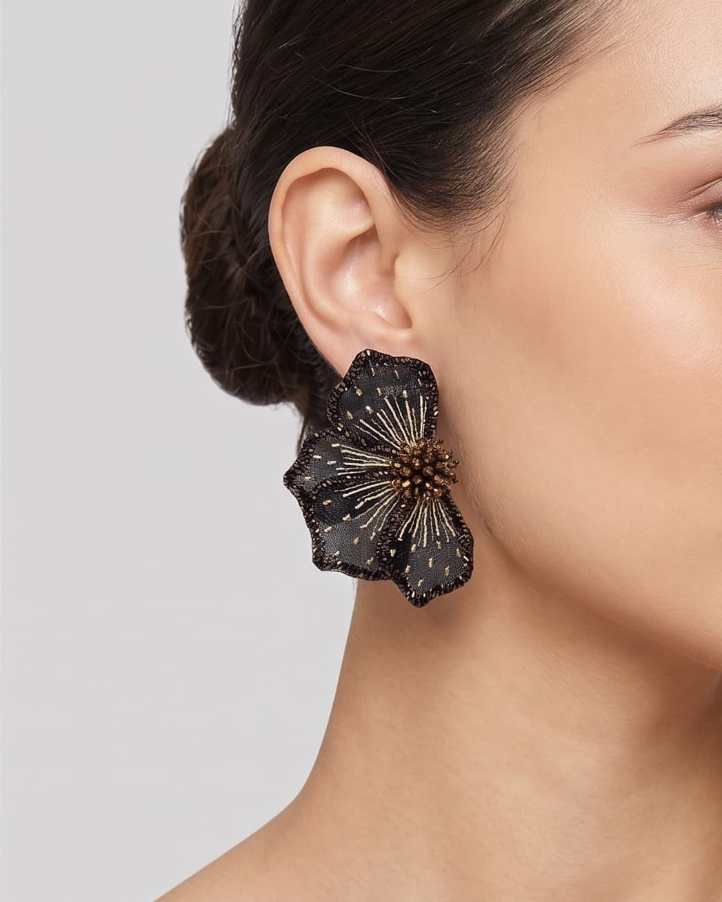 modelo luciendo el pendiente Fleur Noire et Bronze en la oreja, apreciando su silueta en abanico y escala sobre la piel.