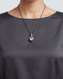modelo luciendo el Collar Lucca de Maria e Luisa sobre una prenda oscura, apreciando la caída de la cadena y la escala del colgante.