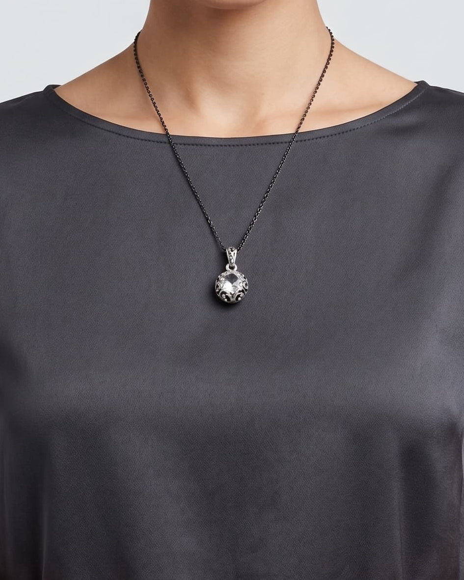 modelo luciendo el Collar Lucca de Maria e Luisa sobre una prenda oscura, apreciando la caída de la cadena y la escala del colgante.