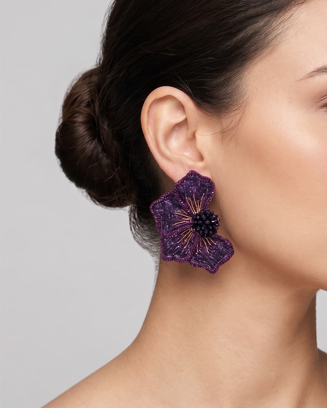 modelo luciendo el pendiente Fleur Violette en la oreja, apreciando su silueta en abanico y profundidad de color sobre la piel.