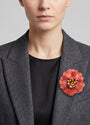 vista frontal del broche de flor de Ciléa Paris colocado en la solapa de una chaqueta de sastre gris, detallando su escala maxi y su elegancia cromática.