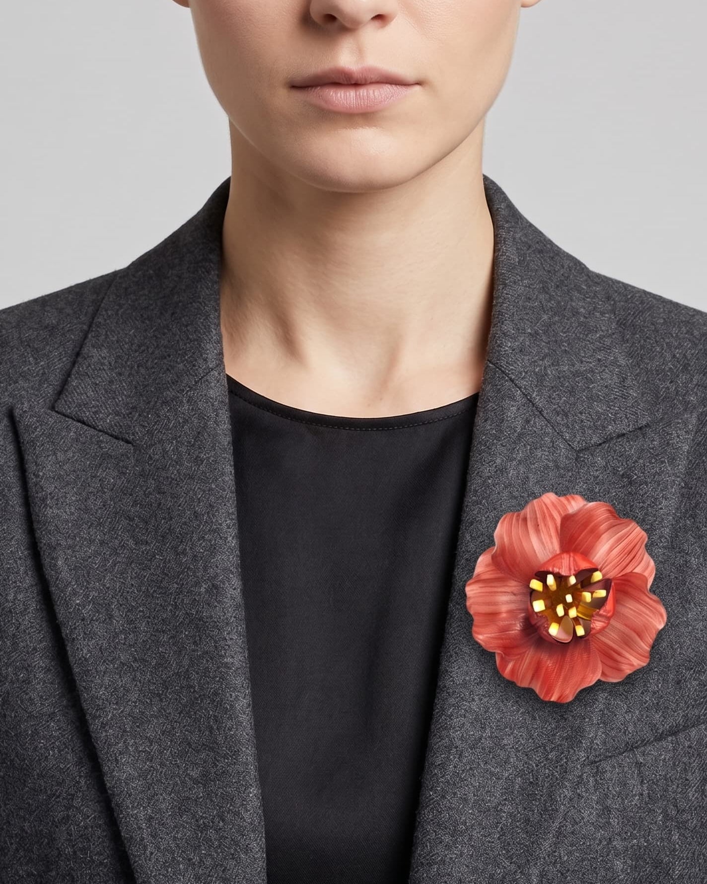 vista frontal del broche de flor de Ciléa Paris colocado en la solapa de una chaqueta de sastre gris, detallando su escala maxi y su elegancia cromática.