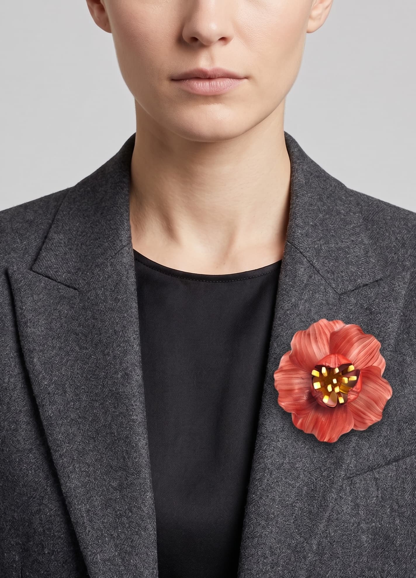 vista frontal del broche de flor de Ciléa Paris colocado en la solapa de una chaqueta de sastre gris, detallando su escala maxi y su elegancia cromática.