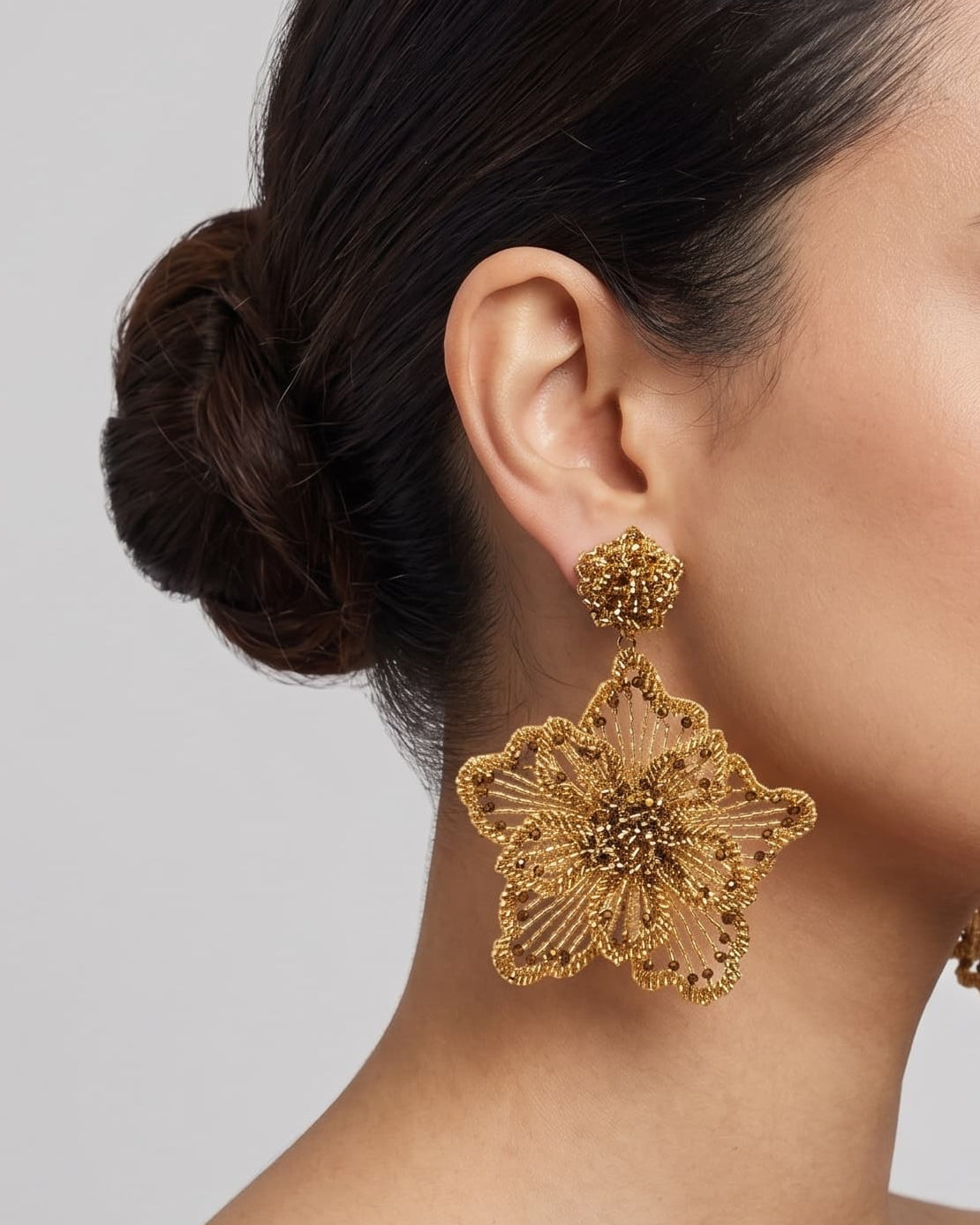 modelo luciendo el pendiente Fleur Dorée en la oreja, apreciando su escala maxi, resplandor metálico y volumen sobre la piel.