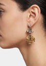Mujer luciendo los pendientes "Trilogía Áurea", destacando su volumen y el brillo de los cristales superiores.