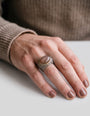 Anillo ancho de plata con cabujón ovalado marrón visto puesto en la mano de una modelo