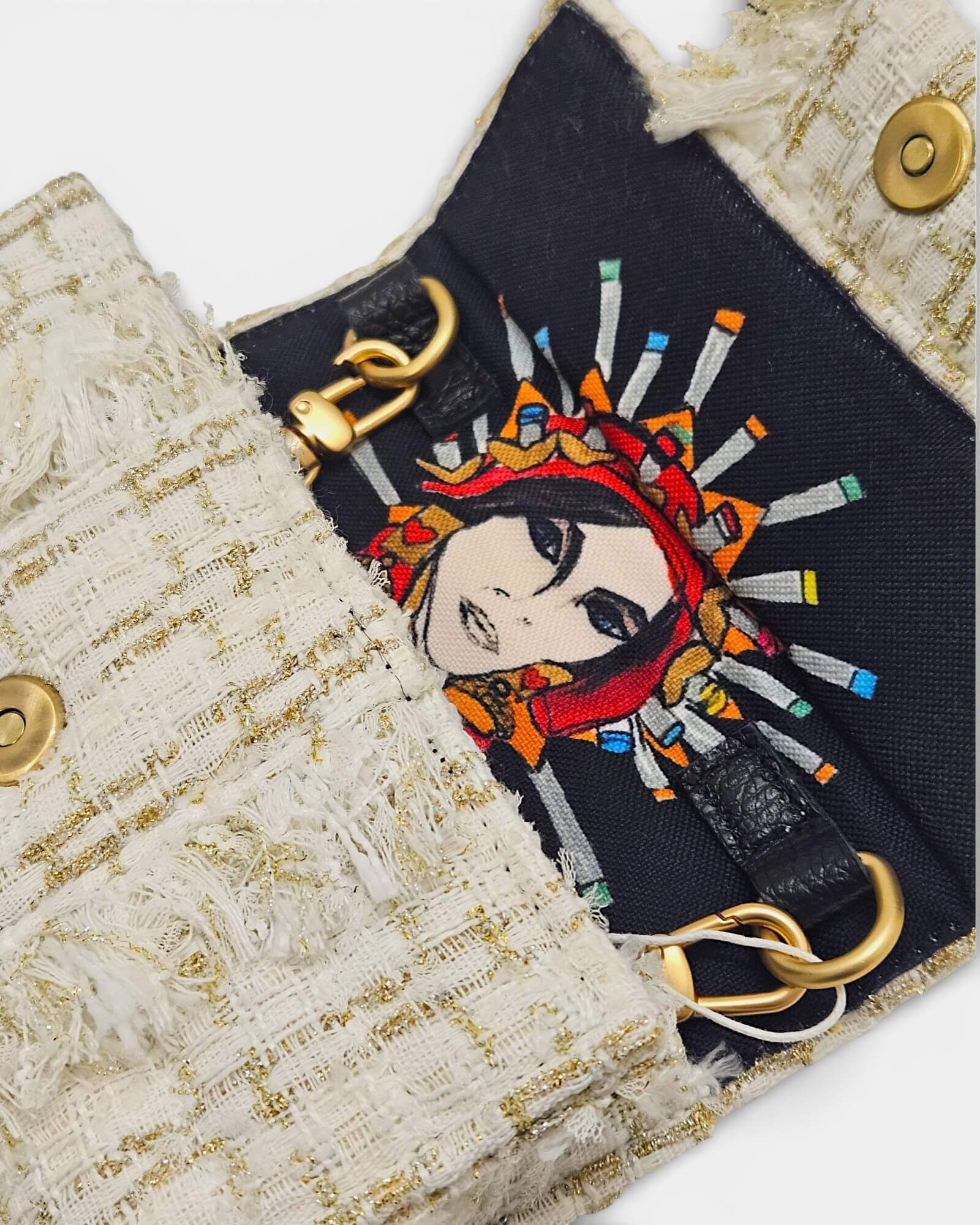 Detalle del interior de un bolso Kooreloo mostrando un forro de tela negra con una ilustración artística de un rostro femenino.