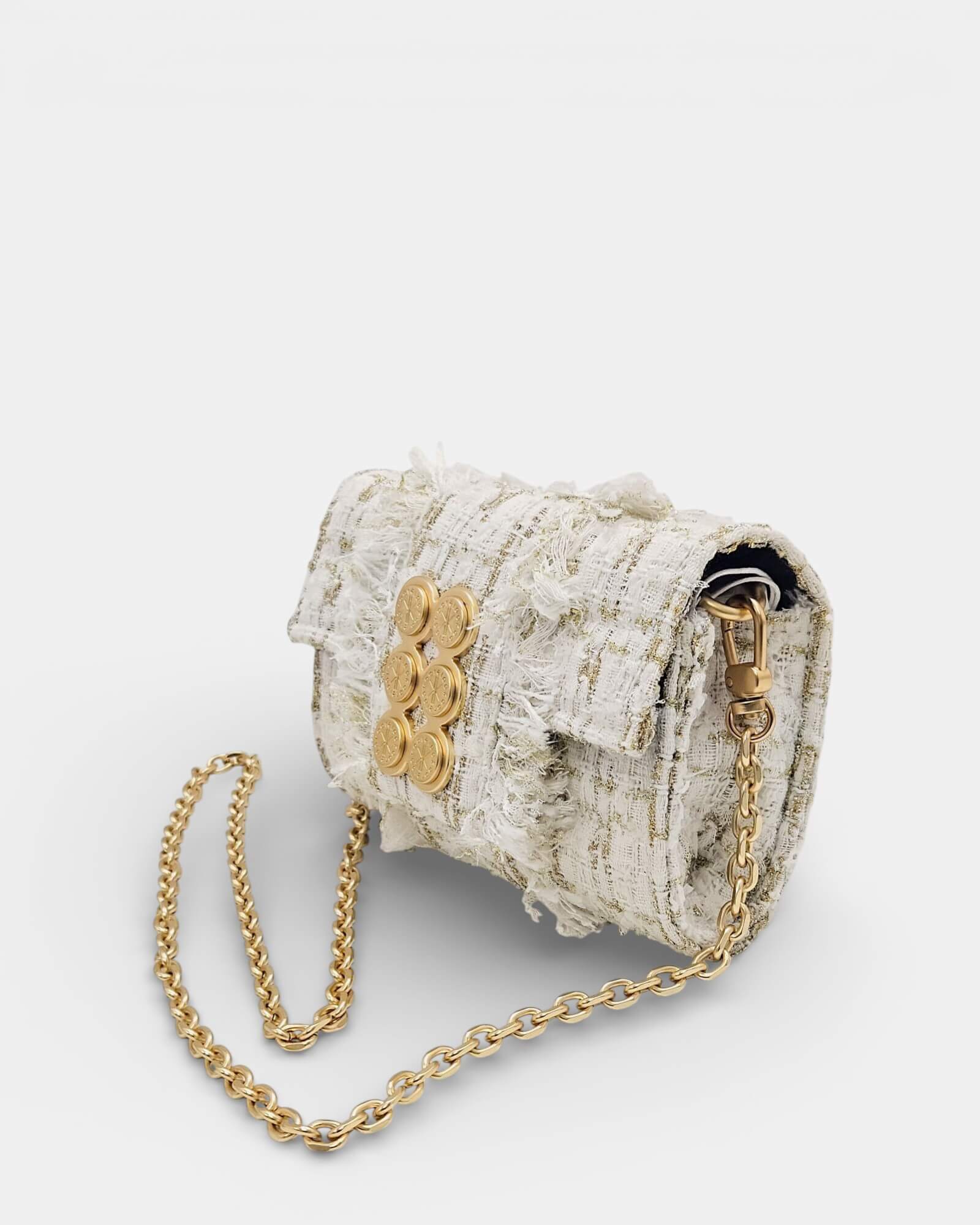Vista en ángulo de un bolso Kooreloo de tweed blanco con hilos dorados, detalles desflecados y correa de cadena dorada.