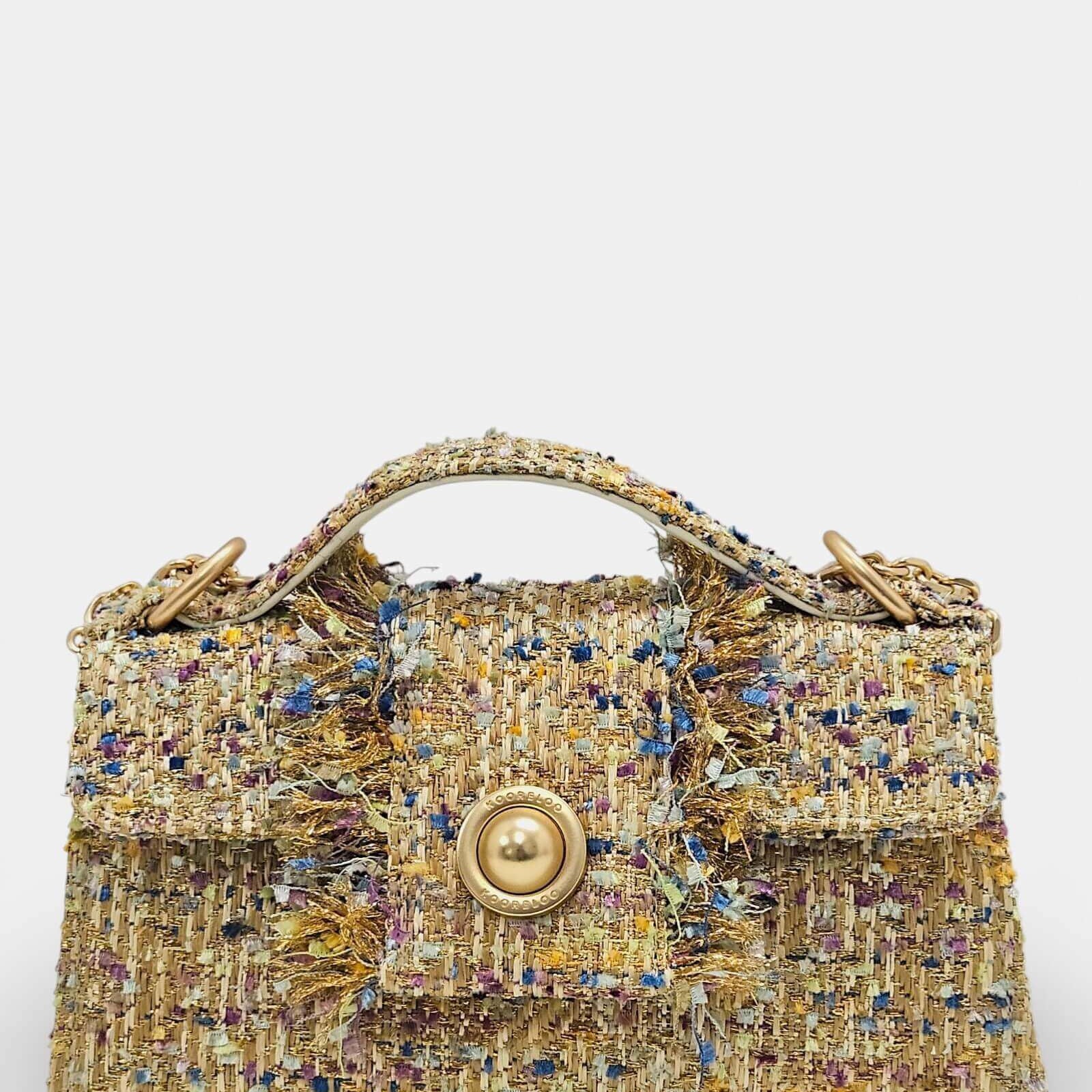 Bolso Kooreloo de tweed con broche circular dorado tipo perla y detalles de flecos dorados.