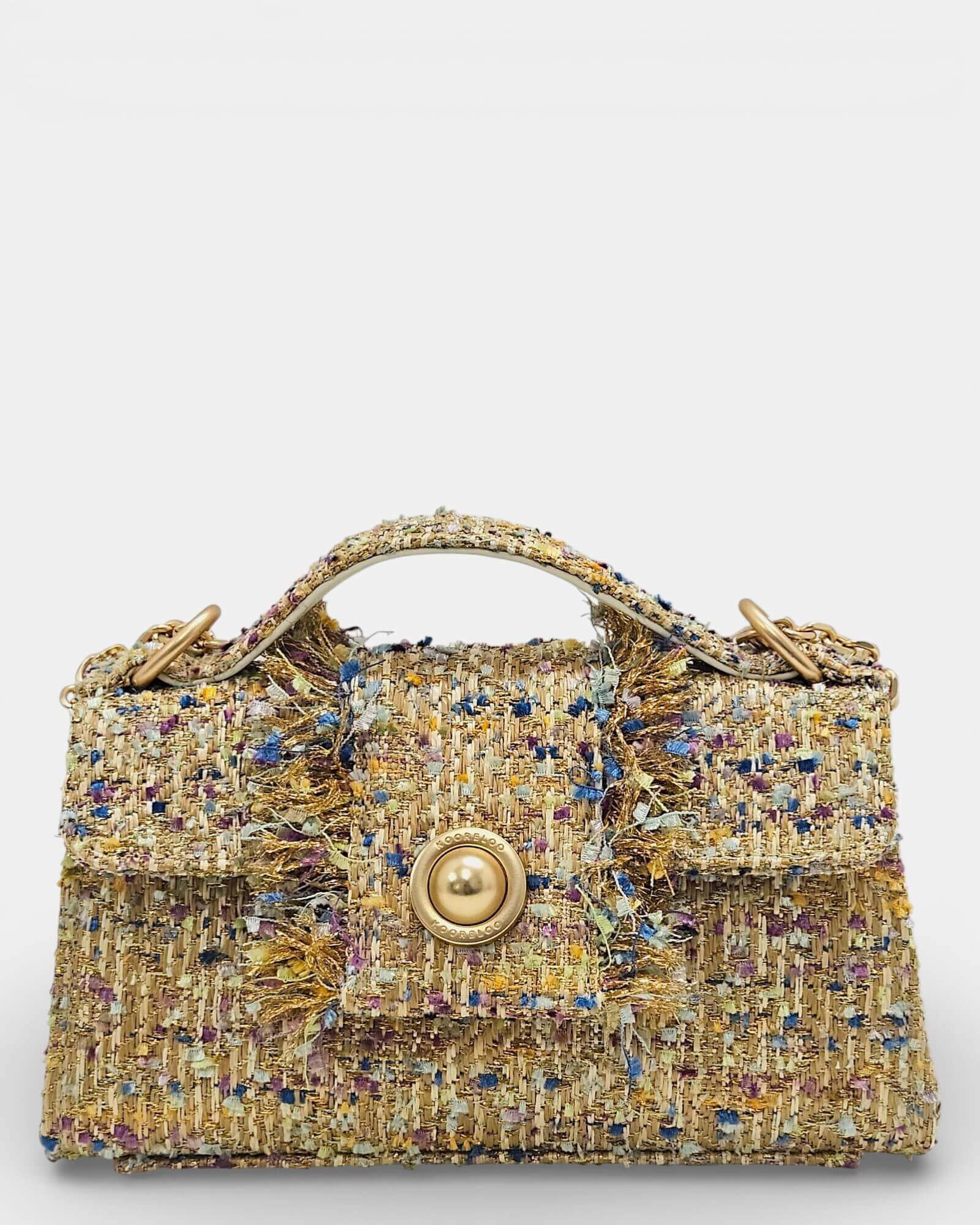Bolso Kooreloo de tweed con broche circular dorado tipo perla y detalles de flecos dorados.