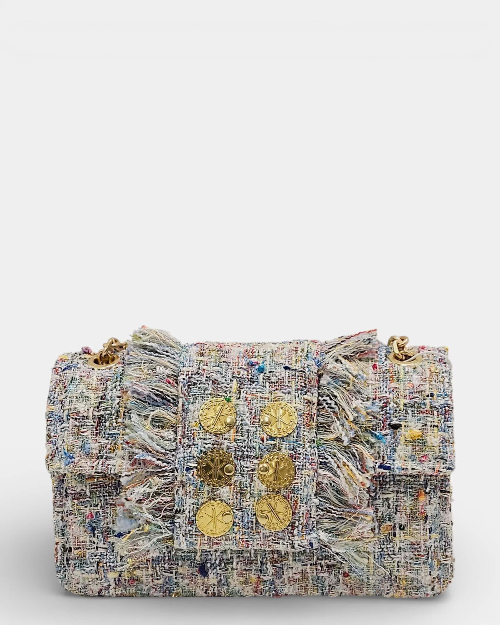 Bolso frontal de tweed en tonos beige y pastel con seis monedas doradas decorativas y laterales con flecos deshilachados.