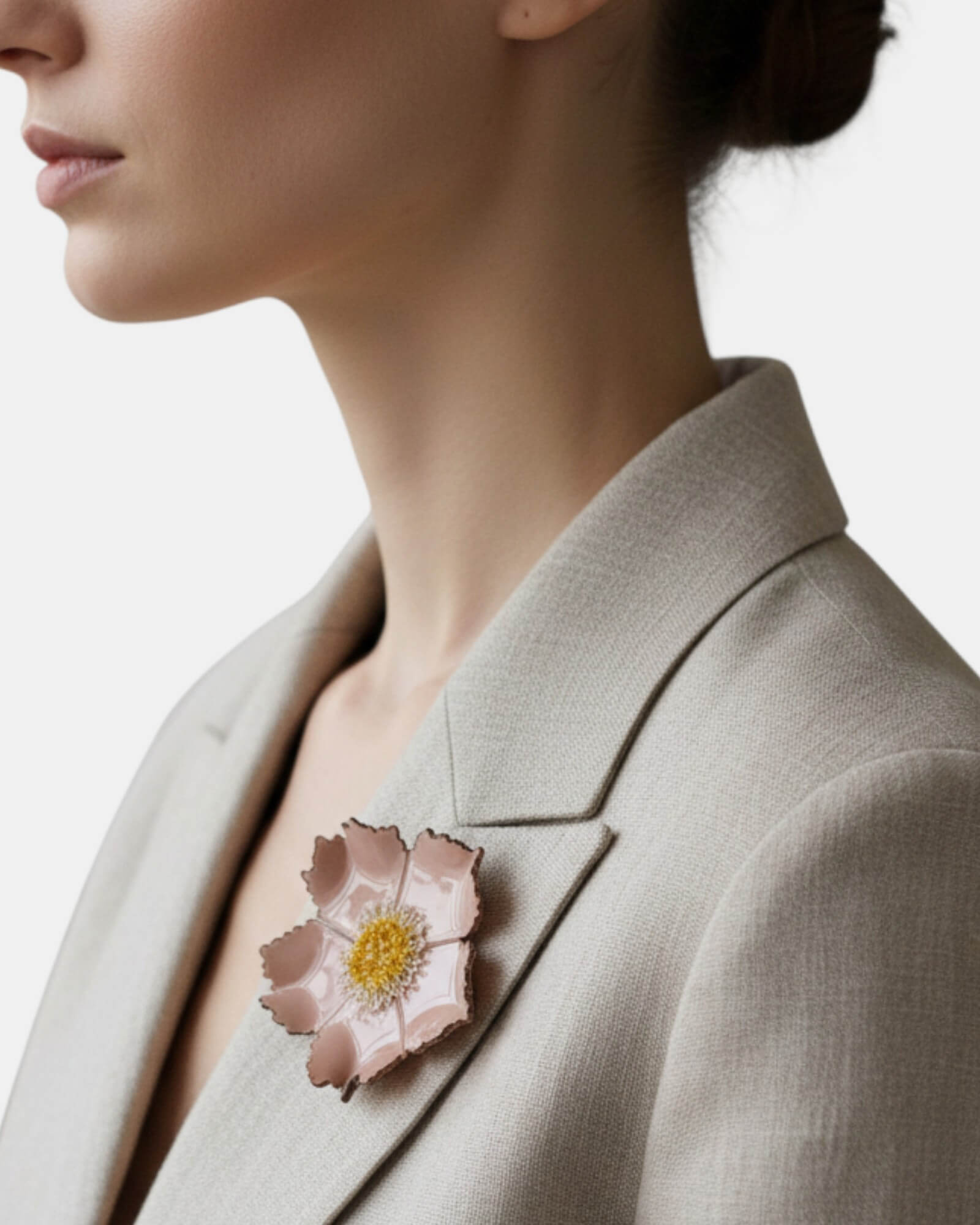 Mujer con blazer beige luciendo un broche de flor silvestre nude en la solapa, estilo natural y elegante.