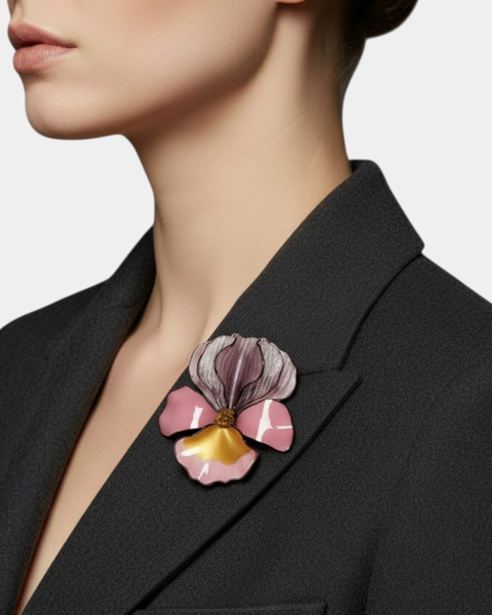 Mujer con blazer gris marengo luciendo el broche de iris rosa y oro, aportando un toque de color femenino y sofisticado.