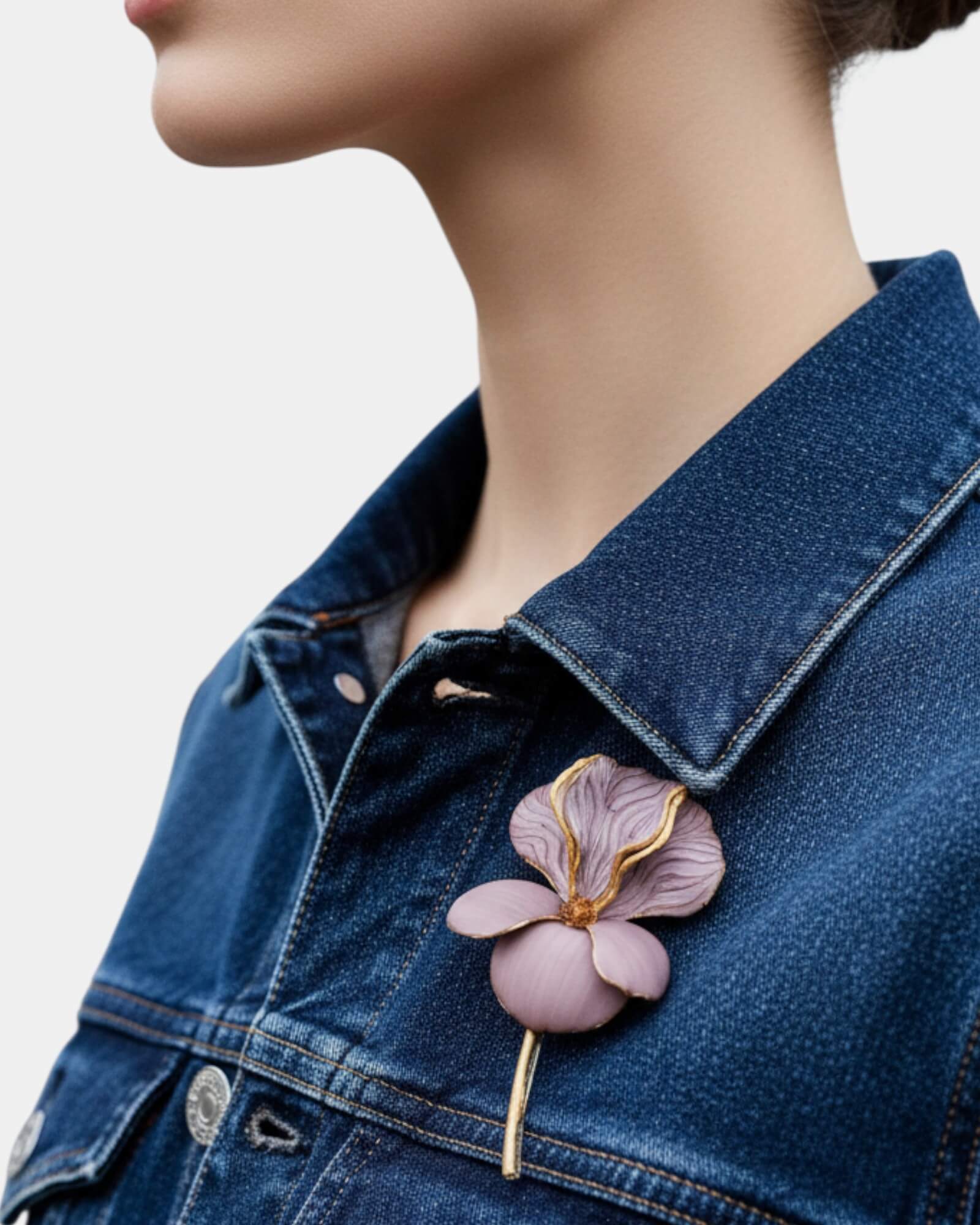 Mujer luciendo un broche floral de diseño sobre una chaqueta vaquera azul, tendencia de accesorios botánicos.