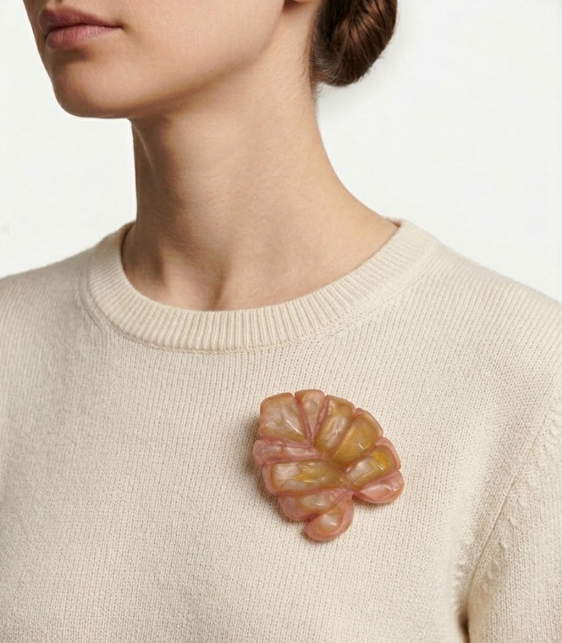 Mujer luciendo el broche statement Jamile Rosewood en la solapa de un mono de lino blanco, resaltando su volumen y elegancia parisina.