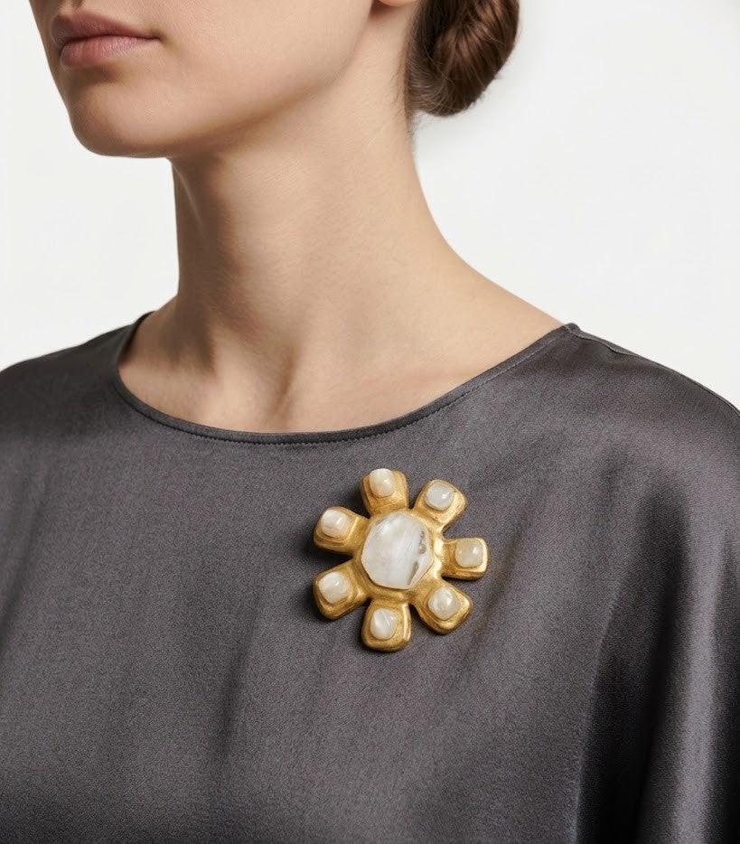 Mujer luciendo el broche Inna Nacre sobre un vestido de seda gris, destacando su brillo y elegancia de lujo silencioso.