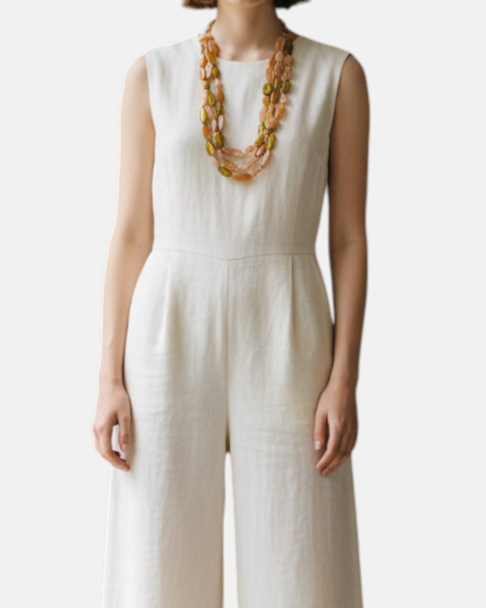 Mujer luciendo el collar statement Ophelia sobre un mono de lino blanco, resaltando su volumen y elegancia parisina.