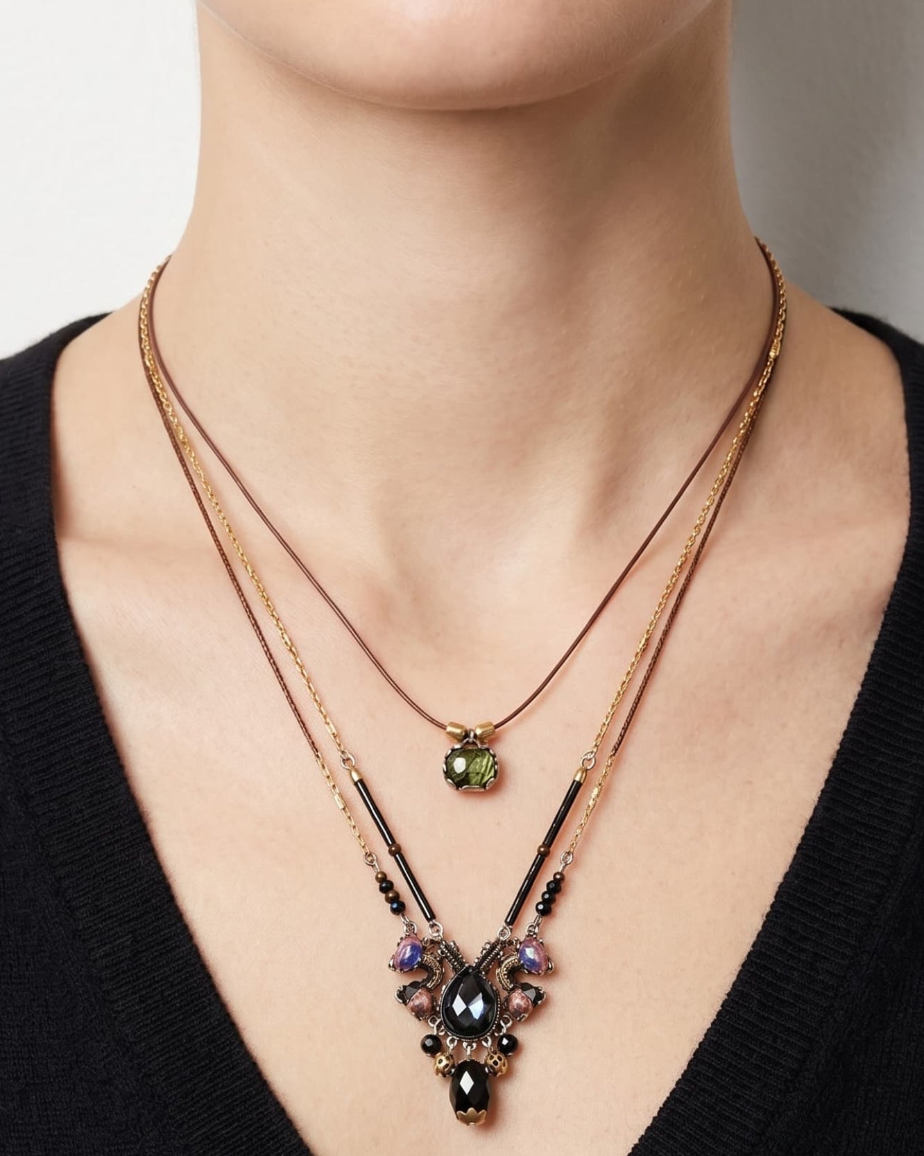 modelo luciendo el collar de doble caída de Ayala Bar sobre un jersey negro de escote en pico, mostrando el efecto bohemio y escalonado del cabujón verde y el motivo central oscuro.