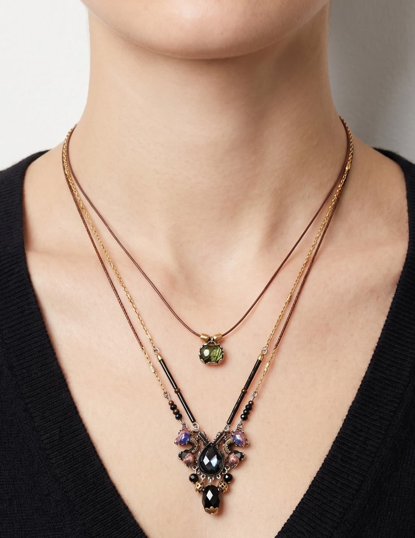 modelo luciendo el collar de doble caída de Ayala Bar sobre un jersey negro de escote en pico, mostrando el efecto bohemio y escalonado del cabujón verde y el motivo central oscuro.
