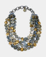 Collar de cuatro hileras Lisa de Dominique Denaive con cuentas circulares en azul, gris nacarado y oro sobre fondo blanco.