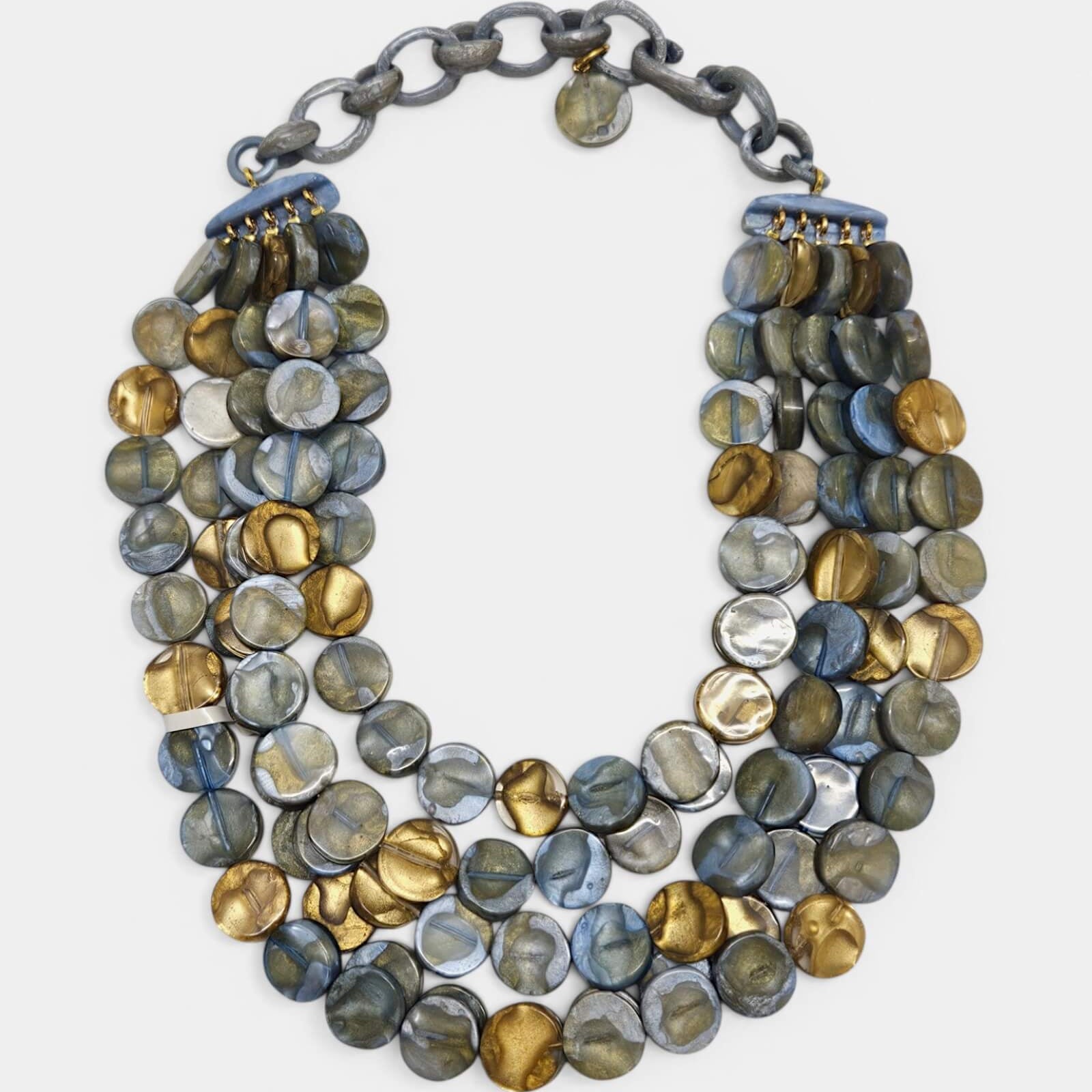 Collar de cuatro hileras Lisa de Dominique Denaive con cuentas circulares en azul, gris nacarado y oro sobre fondo blanco.