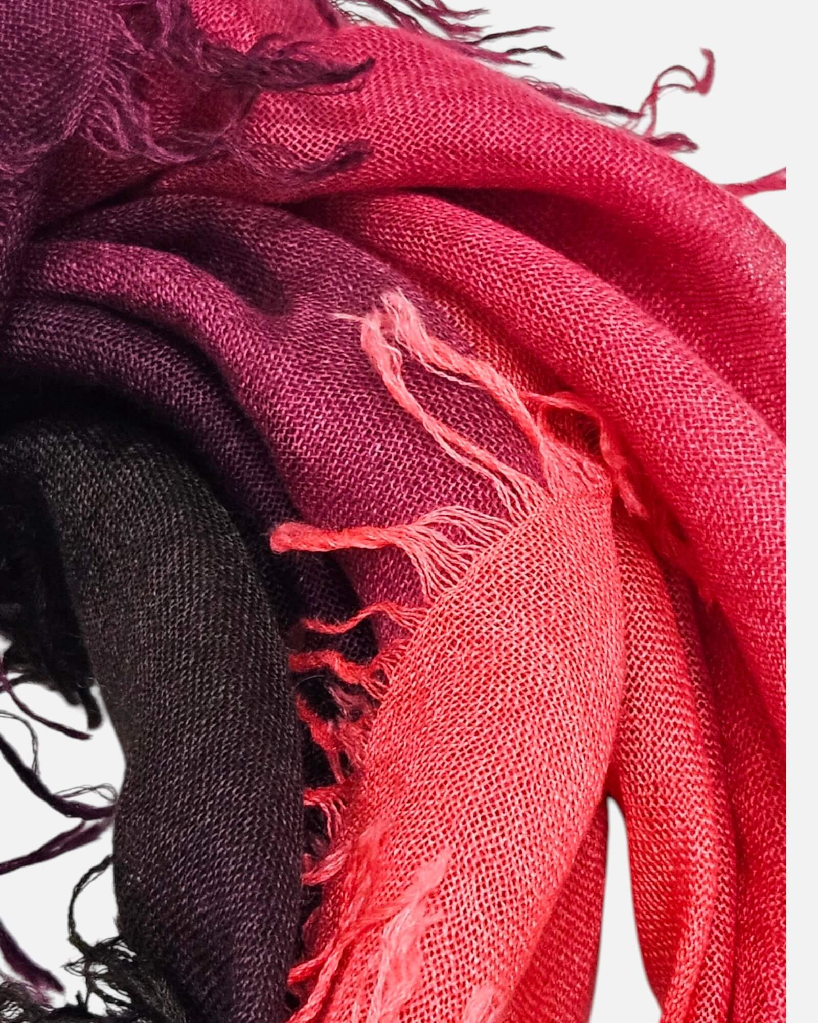 Primer plano del pliegue y textura esponjosa en cashmere y seda del foulard Faliero Sarti Loy mostrando la gradación de coral a negro.