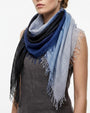 Modelo luciendo el foulard Faliero Sarti Loy doblado en triángulo al cuello con degradado de azul cobalto y gris sobre un top oscuro.