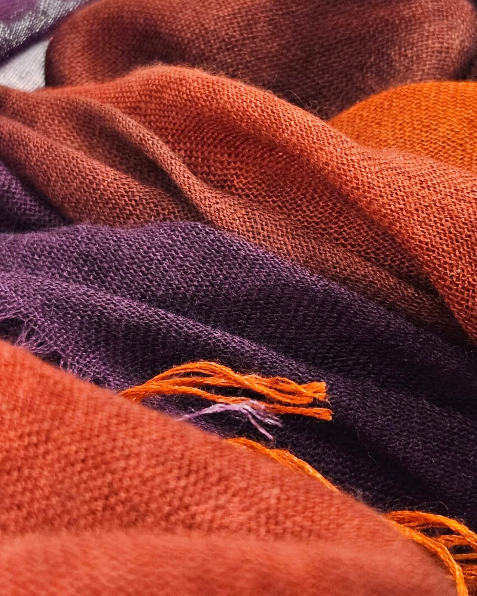 Detalle de las fibras nobles de cashmere y seda del pañuelo Faliero Sarti Enrichetta y sus flecos en tono violeta y naranja caldero.